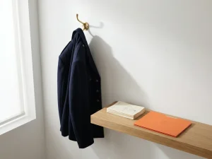 Donkerblauw douane-uniform aan koperen kapstok, officiële documenten met oranje map op eikenhouten plank, natuurlijk licht.