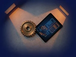 Koperen tandwiel verbonden met digitale tablet met magazijnplattegronden op betonnen ondergrond, oranje accentverlichting werpt geometrische schaduwen