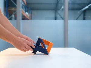 Handen verbinden marineblauw en oranje geometrische vormen boven wit oppervlak, minimalistische compositie met warm zijlicht