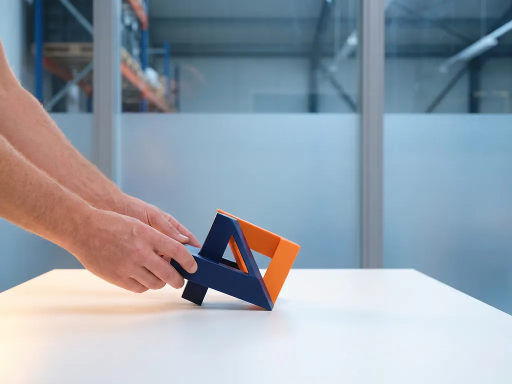 Handen verbinden marineblauw en oranje geometrische vormen boven wit oppervlak, minimalistische compositie met warm zijlicht