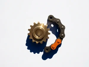 Messing tandwiel grijpt in gebogen kettingschakel op wit oppervlak, marineblauw schaduwspel en oranje accent op verbindingspunt.