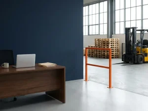 Moderne kantoorwerkplek met laptop naast magazijnvloer met pallets en heftruck in open industriële ruimte met daglicht